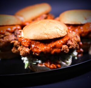 Spicy fried chicken sandwich with toasted bun, coleslaw, and tikka masala sauce