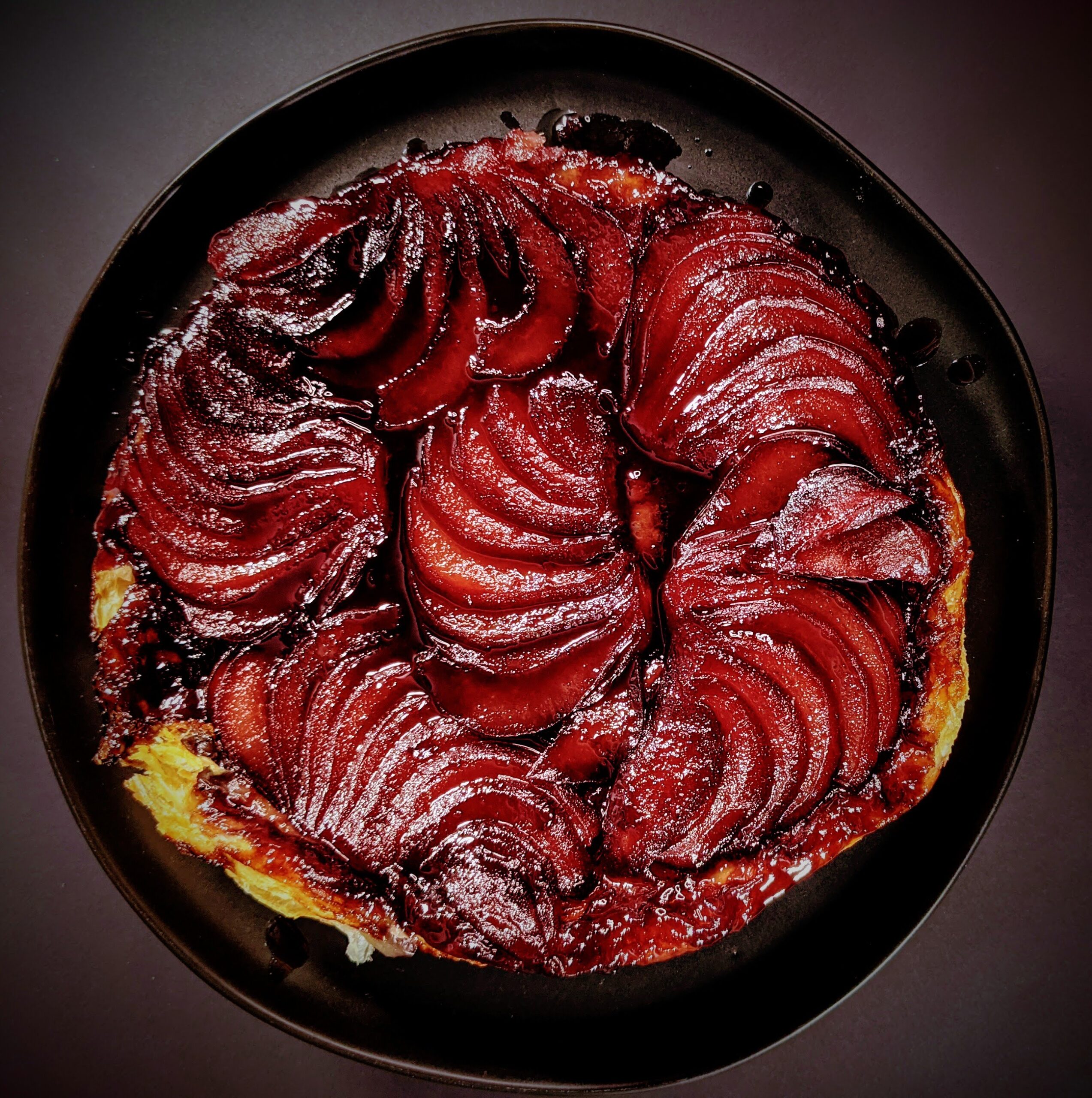 Poached Pear Tarte Tatin on black plate