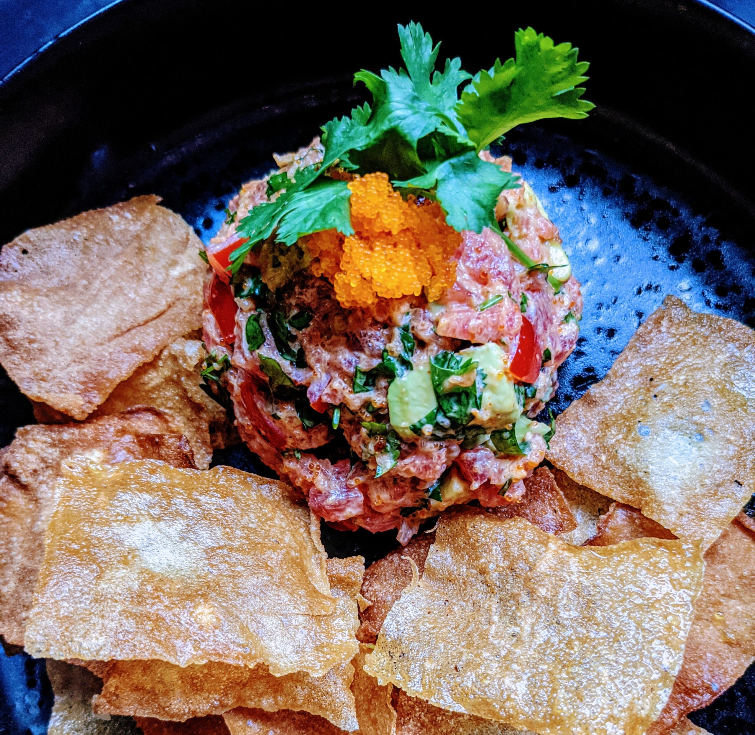 Tuna Tartare and fried eggroll wraps on black plate close shot